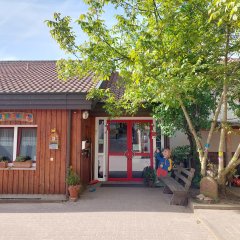 Blicke auf den Eingang des Kindergartens mit einer roten Eingangstür und einem Baum davor