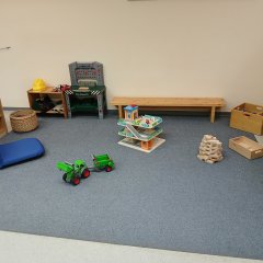 Spielzimmer mit einer kleinen Werkbank, Autoparkhaus und Traktor auf einem Spielteppich