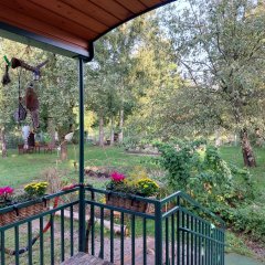 Blick von der Terrasse des Bauwagens des Kindergartens Holla-Bär auf das Gelände mit Wiese, Bäumen und Sandkasten