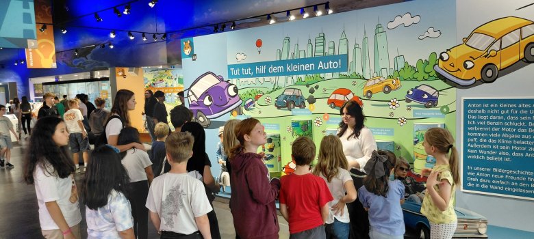 Die Kinder bekommen von einer Mitarbeiterin die Ausstellung erklärt, hier die Ansicht wo man auch ohne Auto zurechtkommen kann